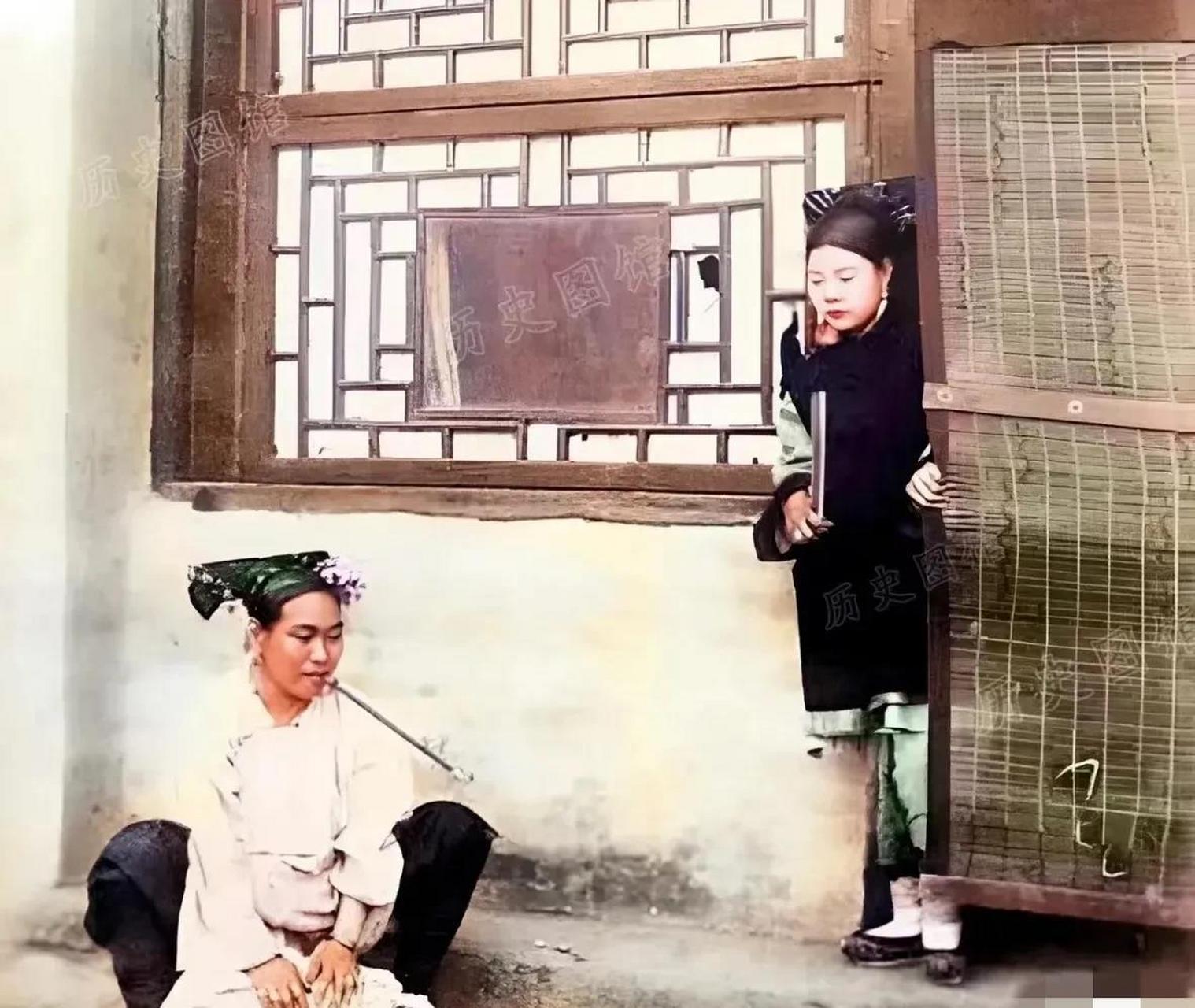 小妾正蹲在地上洗衣服,正妻从屋里走出来,看到她吸着烟干家务,一脸的
