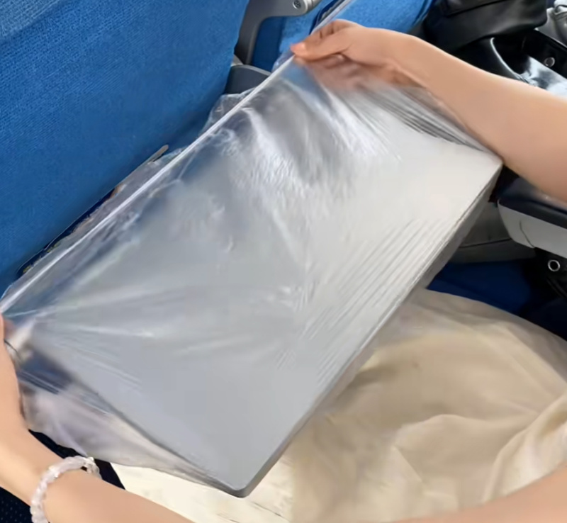 飞机上乘客拆封透明塑料包装盒的场景