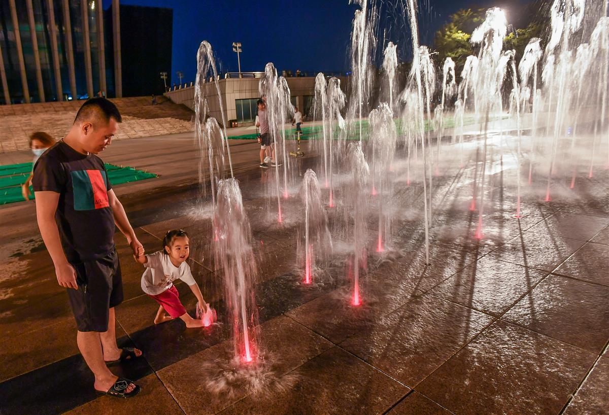 孩子们在喷泉中来回奔跑撒欢,大人拿出手机