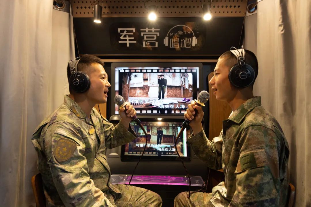 迈入"军营唱吧",班长和新兵小赵头戴耳机,手持麦克风,跟随跃动的音律