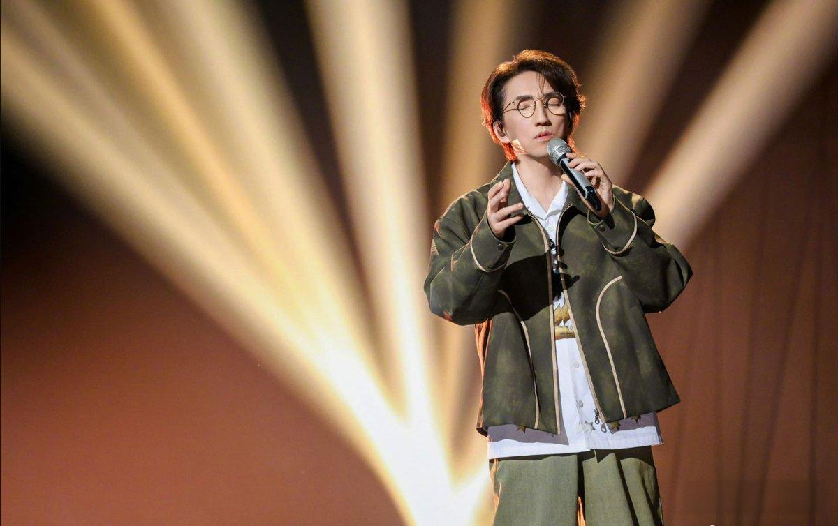 林志炫一位穿着休闲服装,戴眼镜的男歌手在舞台上深情演唱,背景灯光