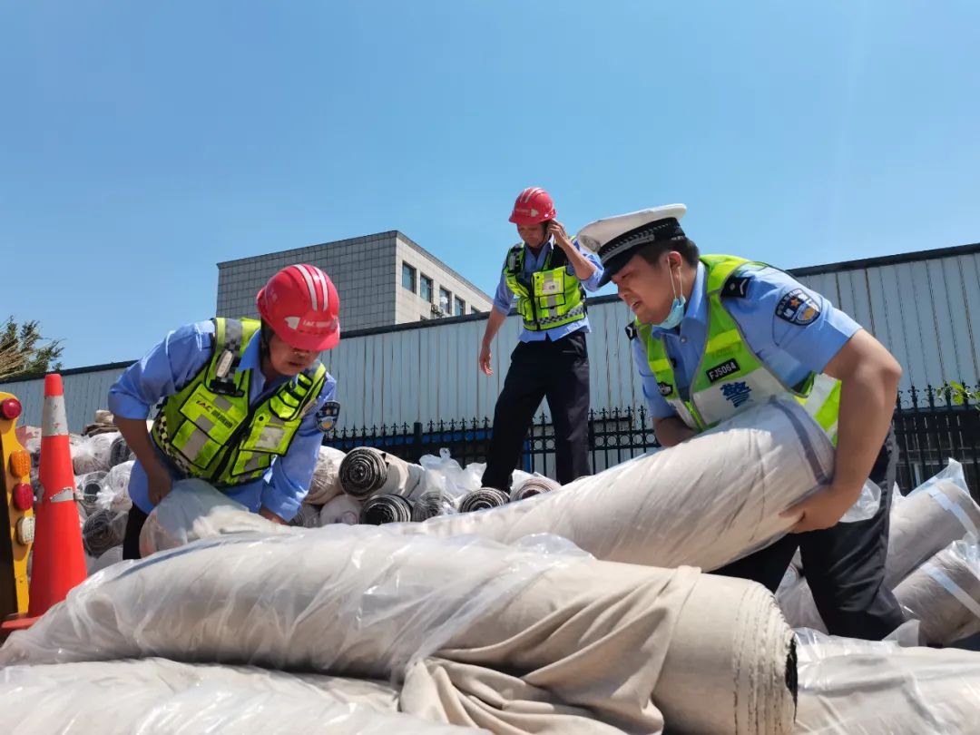 民警蒋继峰,辅警洪飞达与施救单位工作人员一起,将洒落的布匹一捆一捆