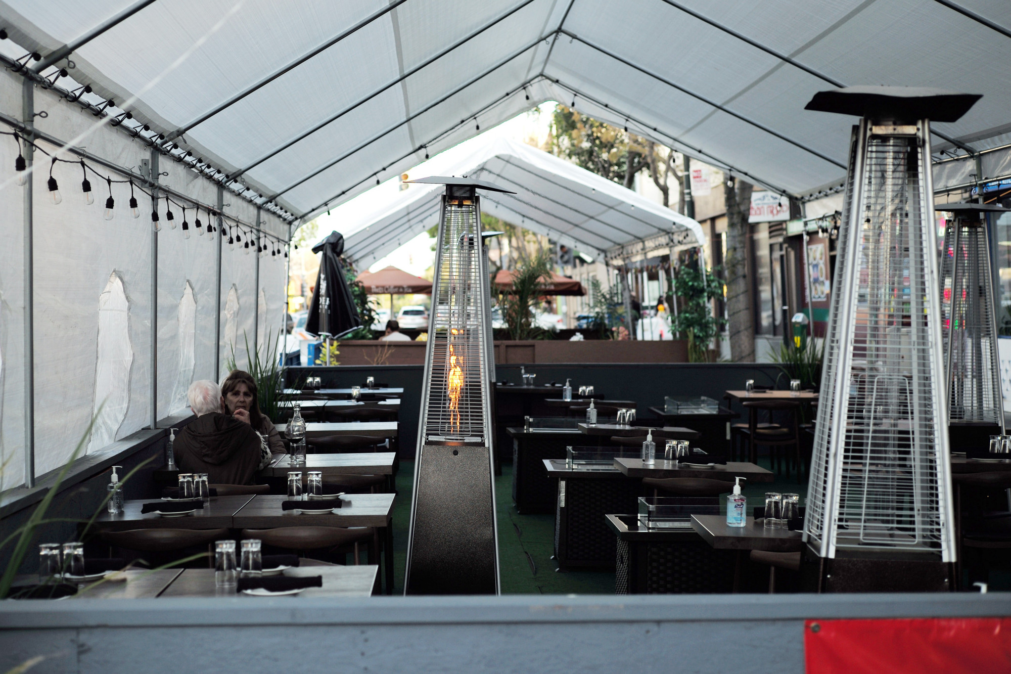 因为疫情,人们在美国加利福尼亚州一家餐厅的户外就餐区用餐.