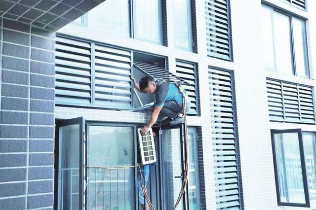 图为安装师傅顶着烈日高空作业为客户安装空调.