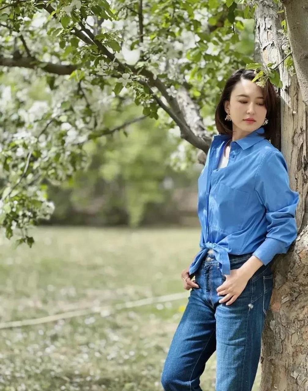 44岁的张蕾,一件蓝色衬衫搭配一条蓝色牛仔裤站在山楂树下,落落大方