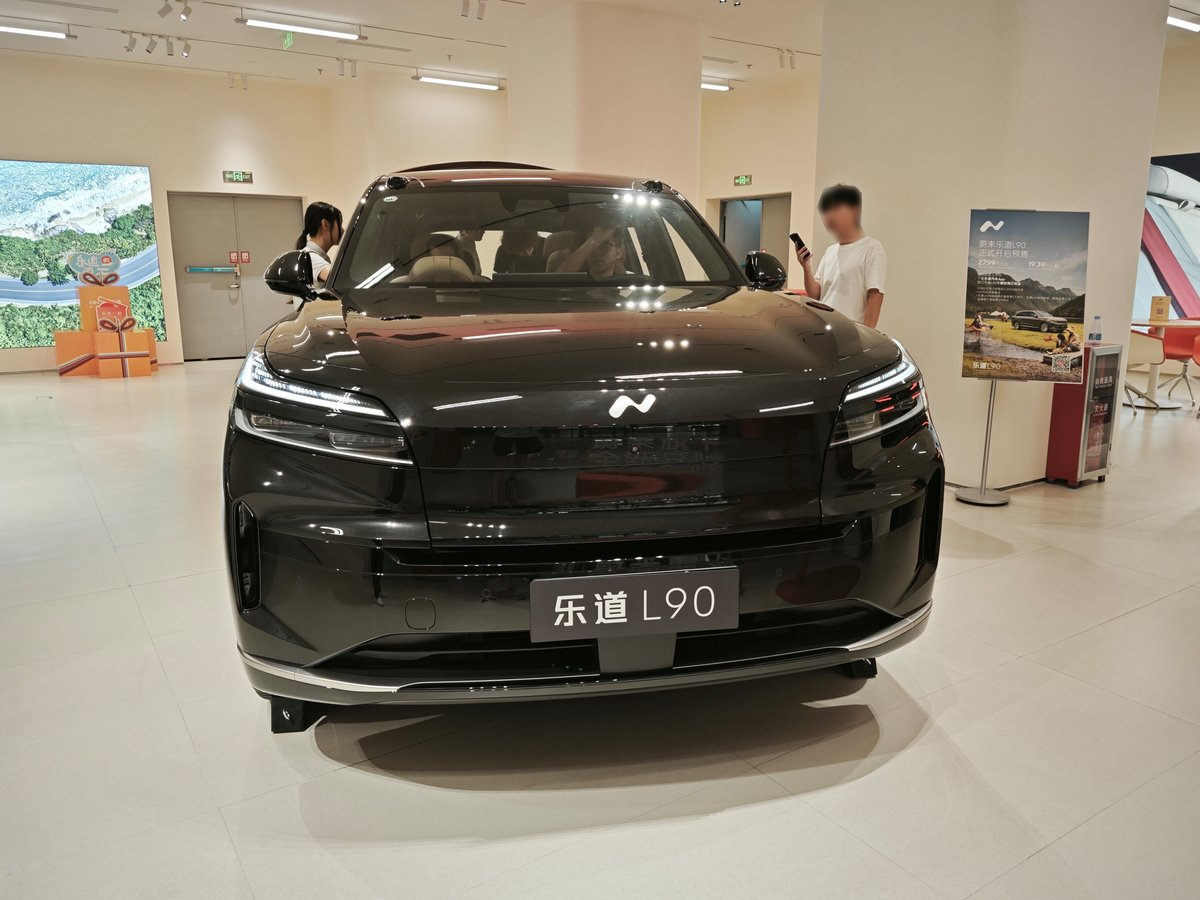 黑色乐道L90电动车展示在展厅内，旁边有人员参观和咨询。