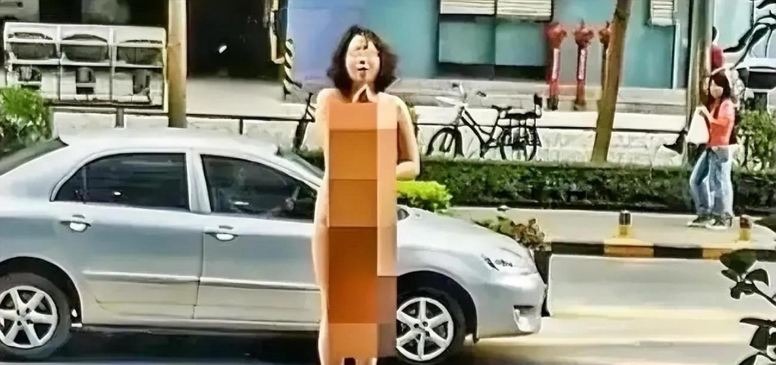 一女子全身赤裸裸的站在街上,抬着头对着楼上的人大骂喊,你不下来我就