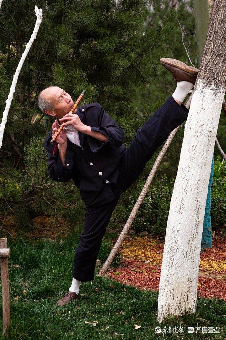 一字马练功不忘吹笛子的老人