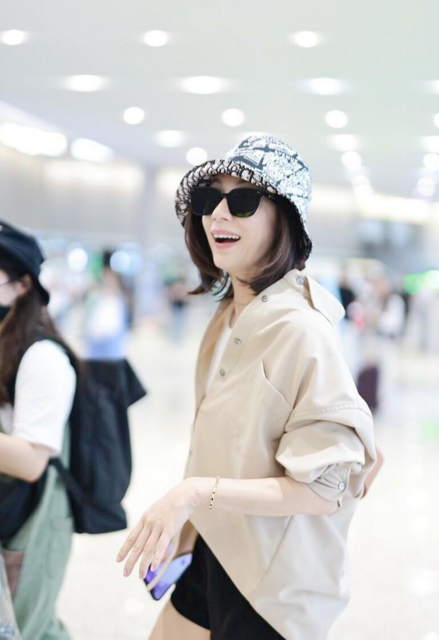 贾静雯机场街拍,卡其色衬衫配白衬衫,黑色短裤 短靴减龄!