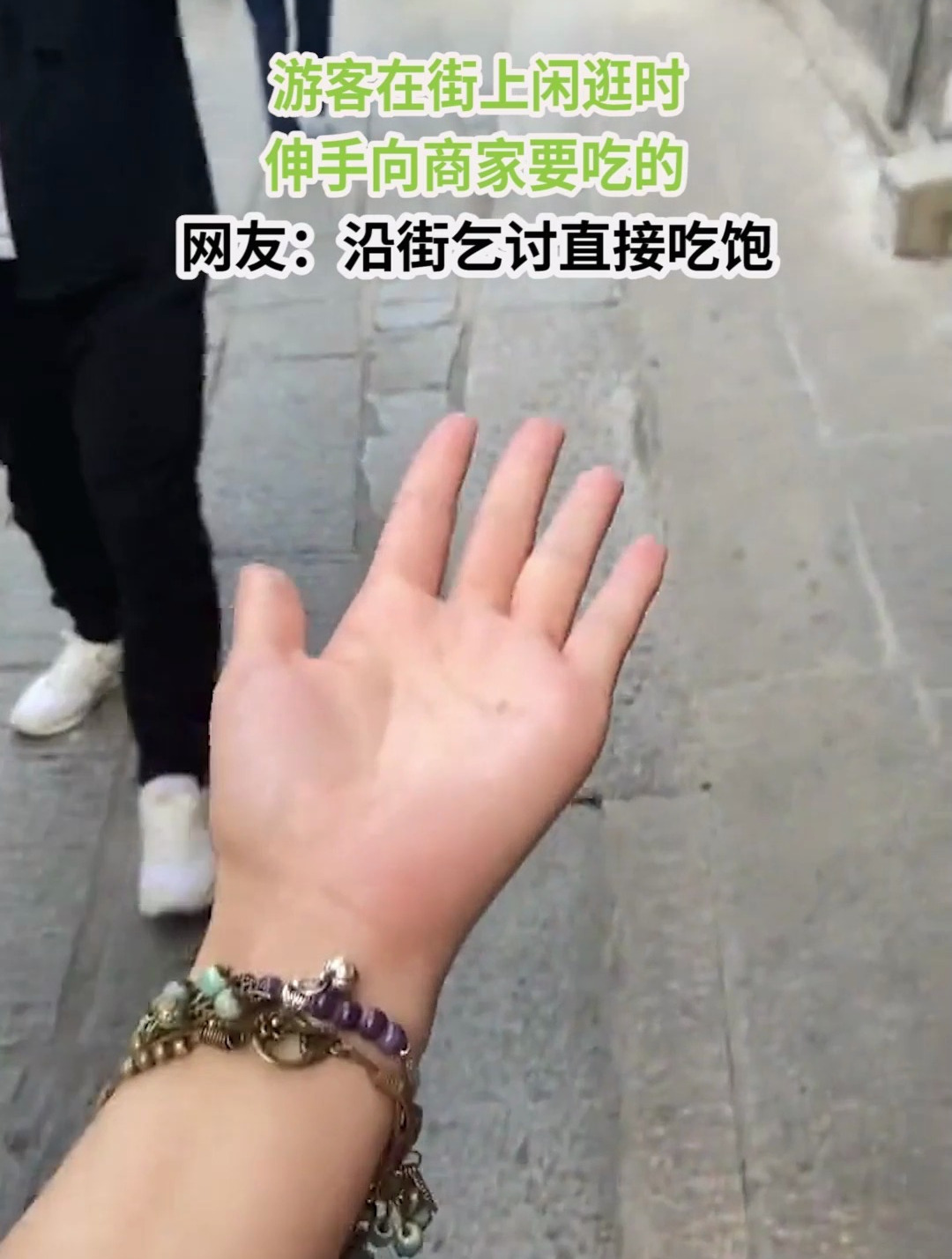 游客在街上闲逛时,伸手向商家要吃的,网友:沿街乞讨直接吃饱
