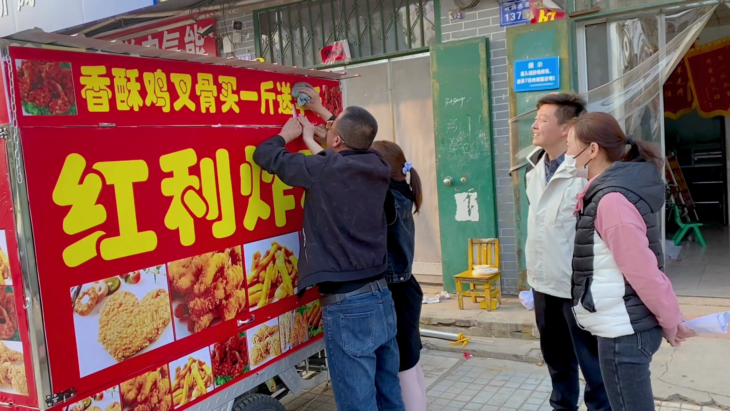 陈宏给三轮量尺寸贴标语,完工效果美观又喜庆,希望生意红红火火