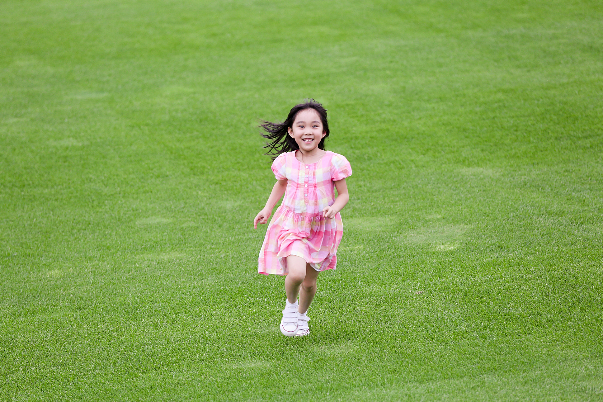 在一片广阔无垠的青青草原上,一个可爱的小女孩张开双臂,欢快地奔跑着
