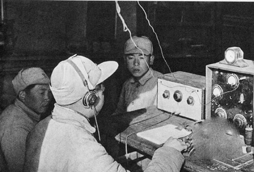 图为新四军部队正在用电台传递战场信息,照片中的战士正在发电报