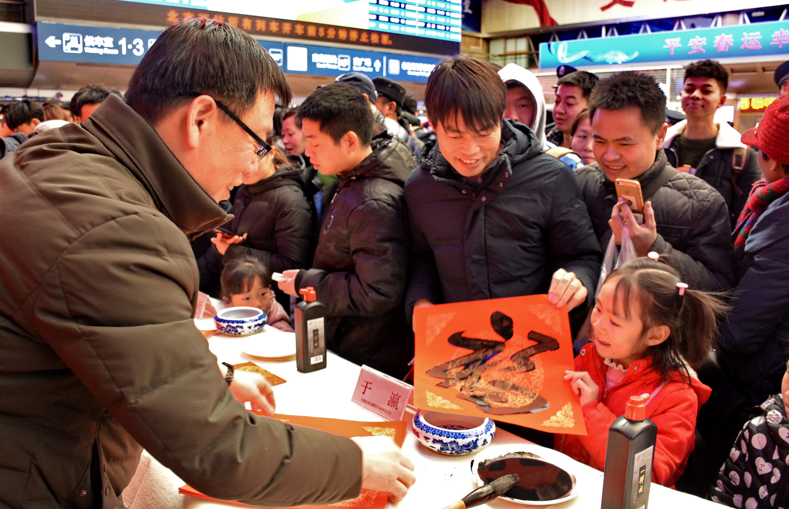 1月20日,书法家在北京西客站为旅客写"福"字和春联.新华社记者李欣摄