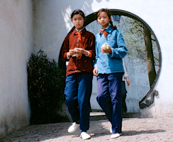 两个女学生迎面走来,带着无比熟悉的红领巾,手里不知道拿的什么东西?