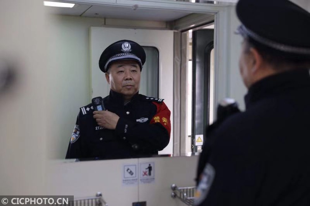 2月24日,乘警杨庆辉对着镜子默默整理警容.