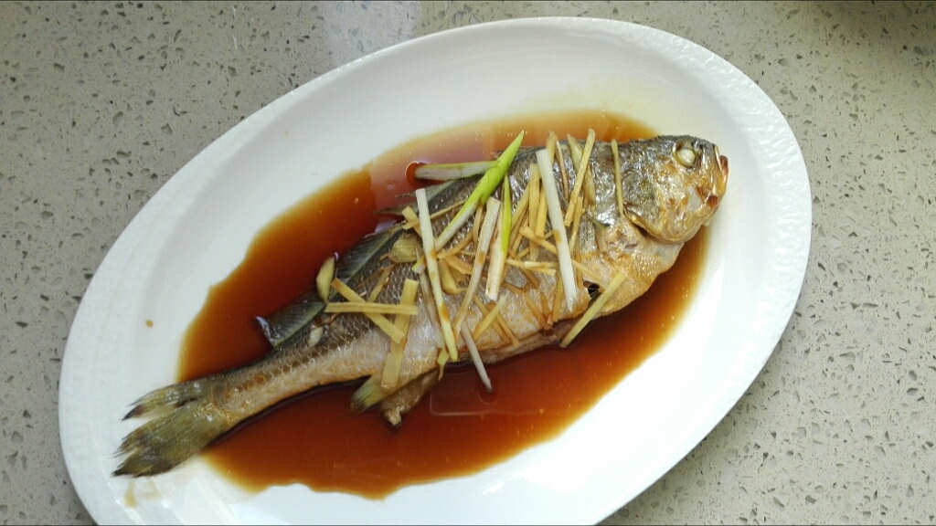 6,将蒸好鱼从锅中取出,倒掉蒸出来的水分,把盘中的葱,姜都去掉,倒入调