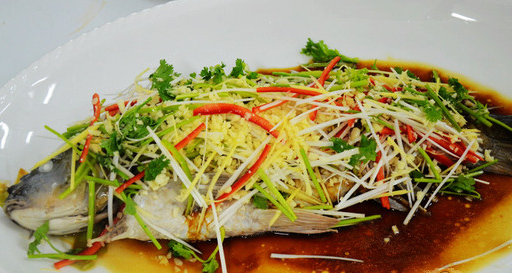 油泼鲤鱼,将鲤鱼鱼身两侧打花刀,炒锅添适量清水,放入鲤鱼烧开