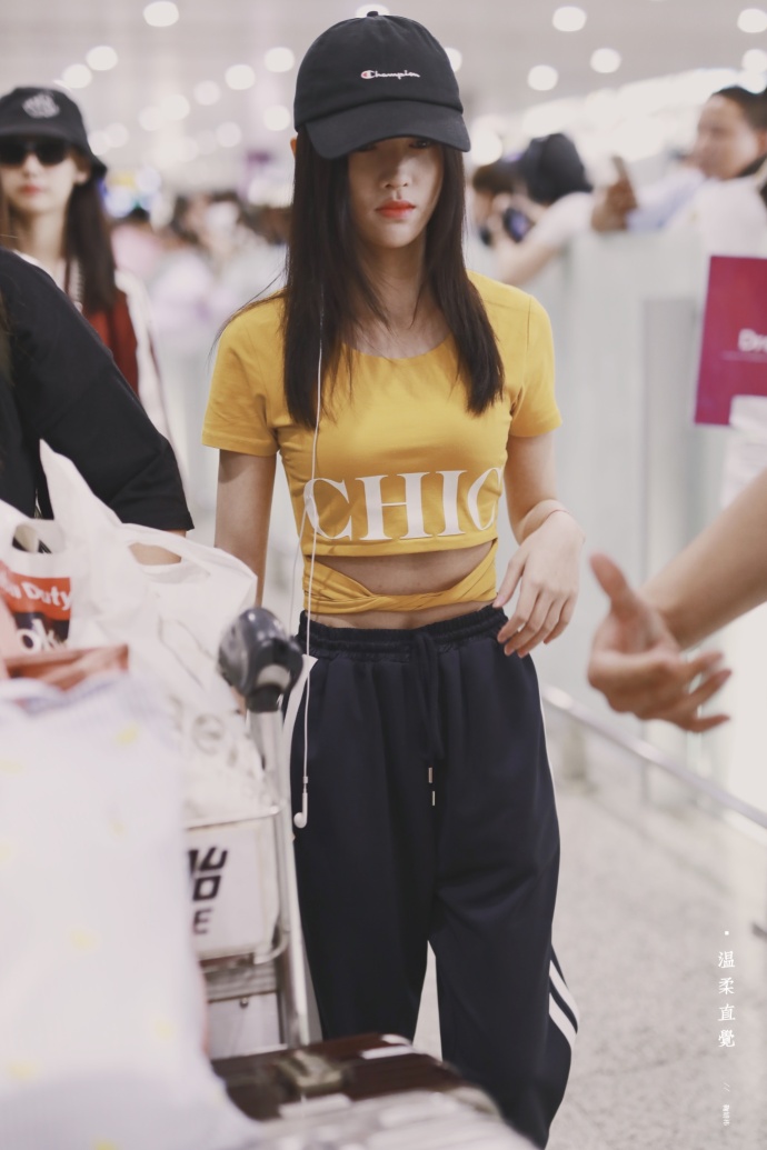 鞠婧祎头戴黑色棒球帽,身穿黄色t恤搭配黑色运动裤,脚踩白色休闲鞋.