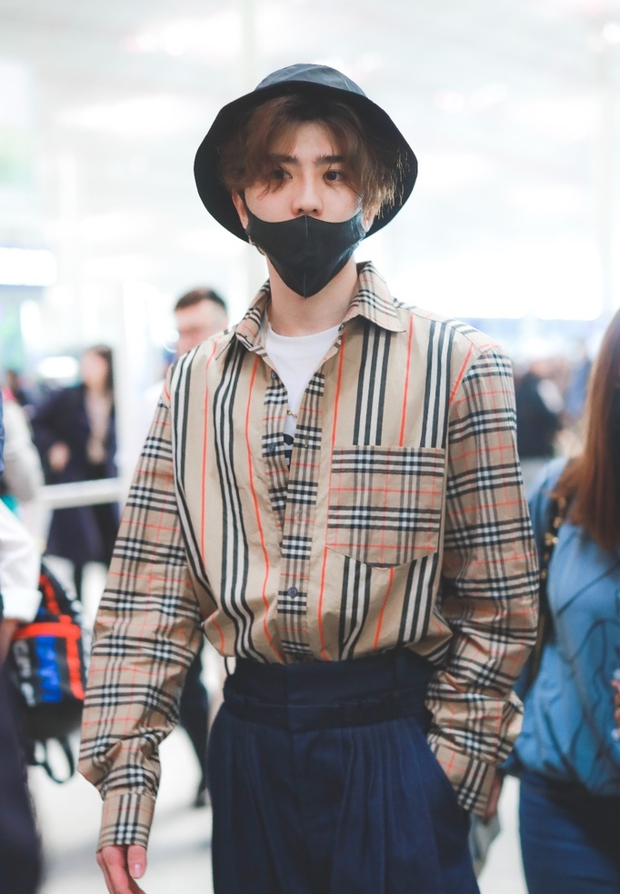 蔡徐坤穿格子衬衫现身机场 头发微卷单手插兜酷劲十足