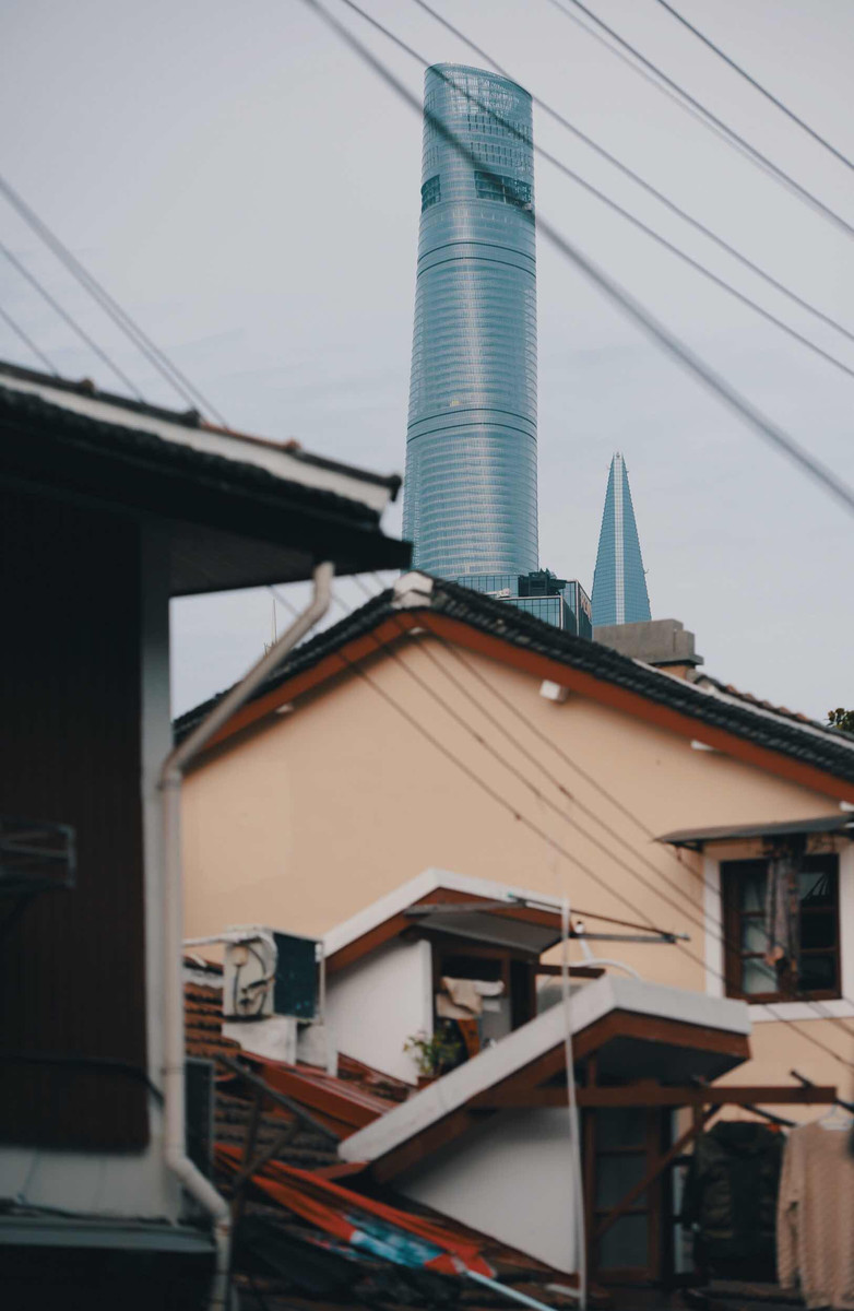 上海老弄堂拍摄,近处低矮杂乱的老房子与远处外滩的现代化建筑形成