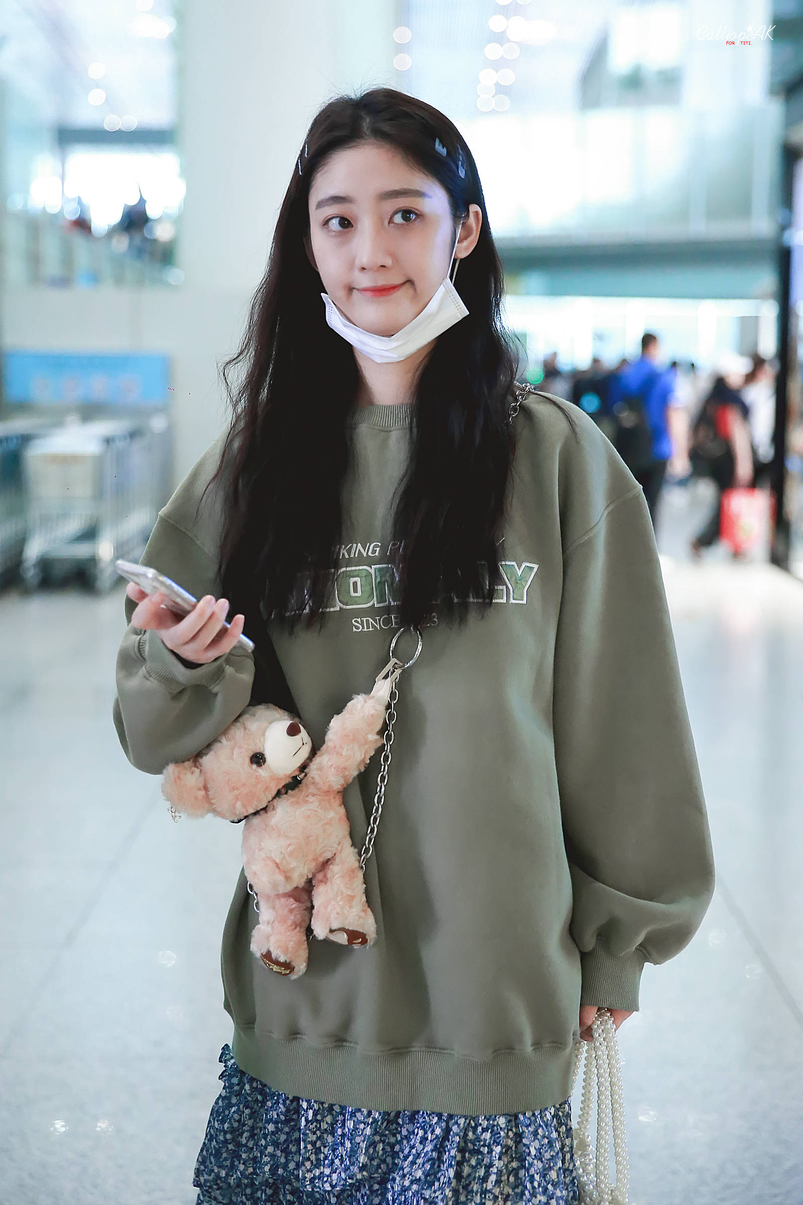戚砚笛穿军绿色卫衣搭配蓝色碎花裙现身机场,皮肤白皙,面带微笑.