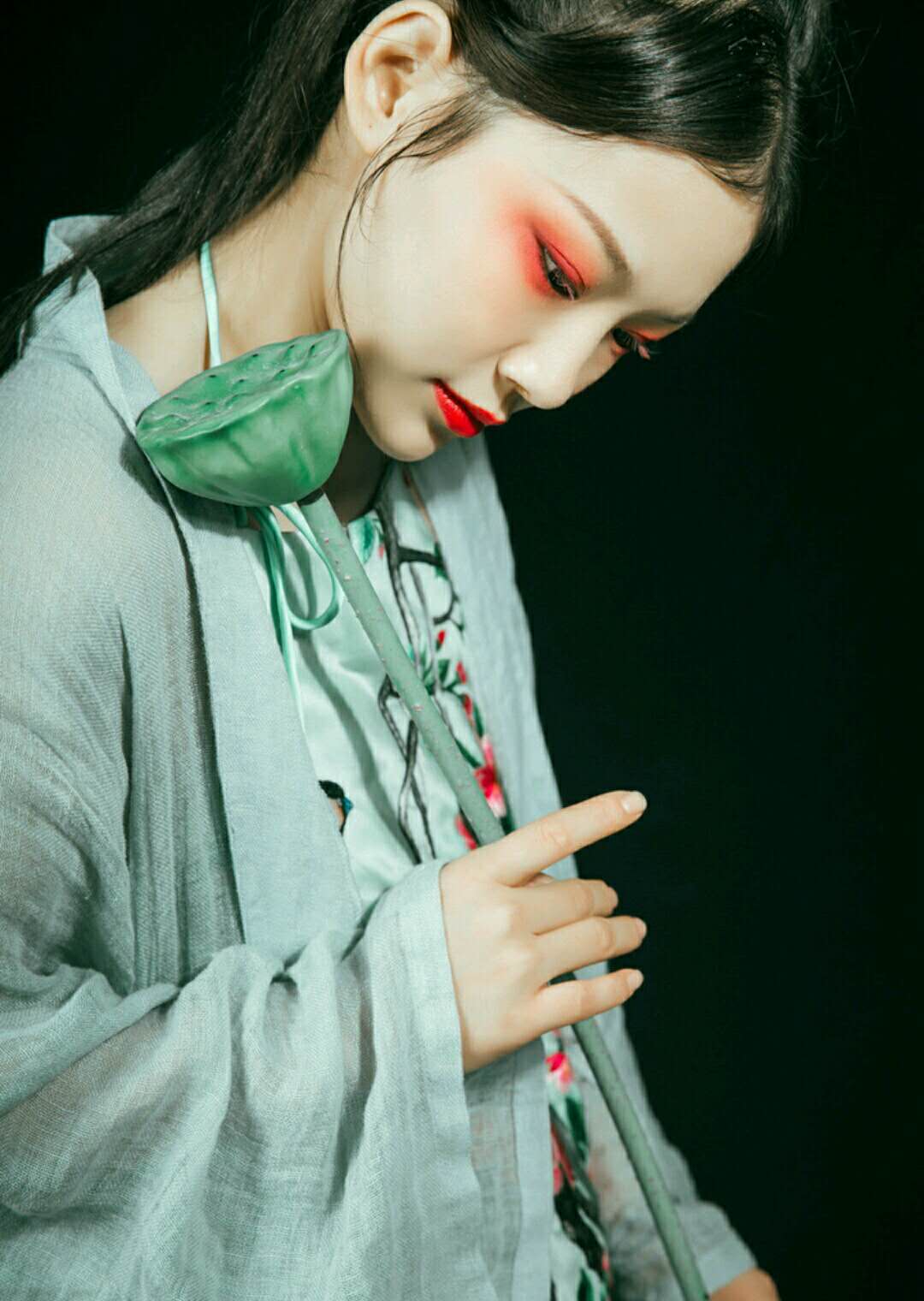 黑色背景下的采莲女怀抱莲蓬,一袭青衫立于江南水乡中