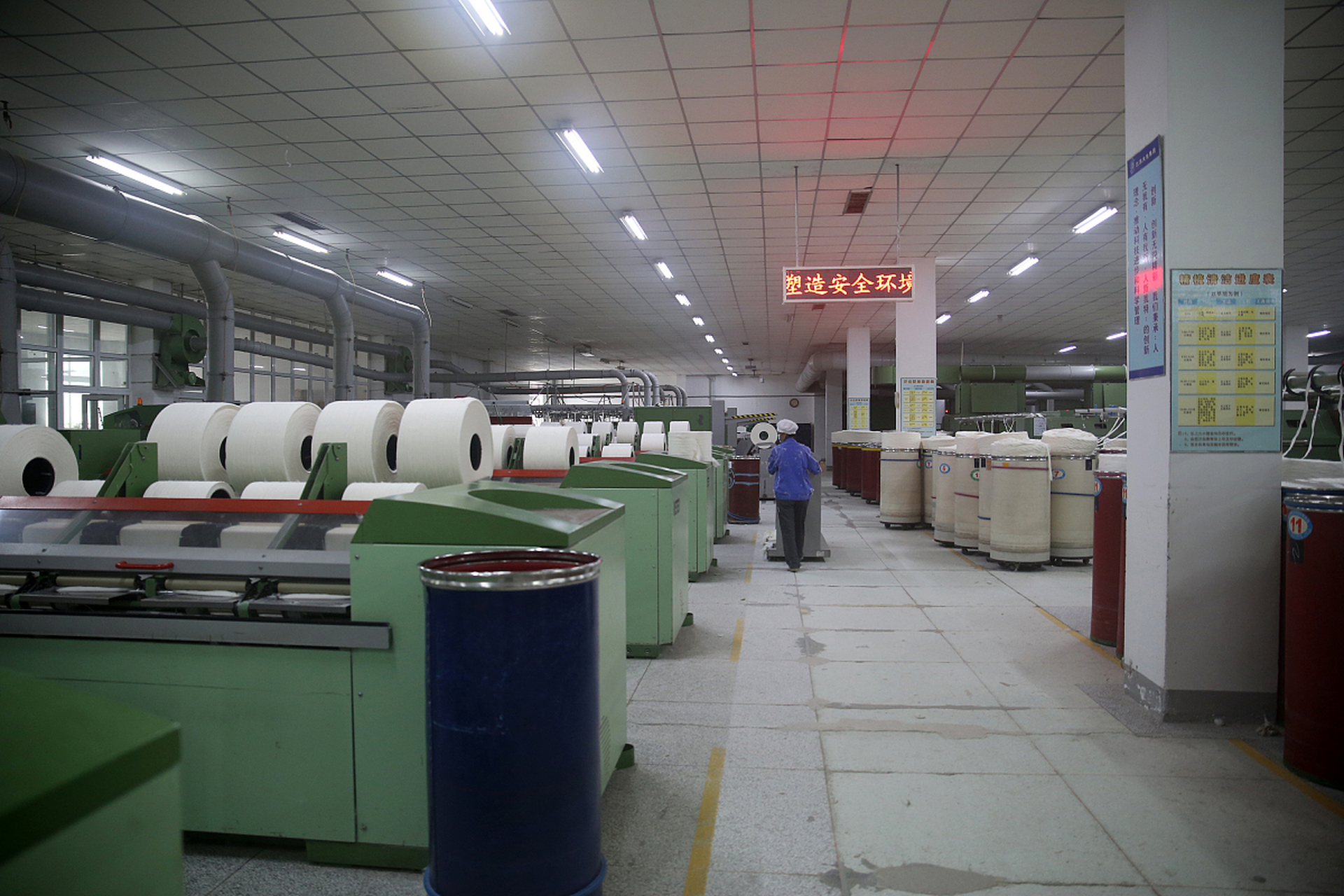 在一家制衣厂的车间中,一位女车工坐在自己的工位上,忙碌地做着制衣