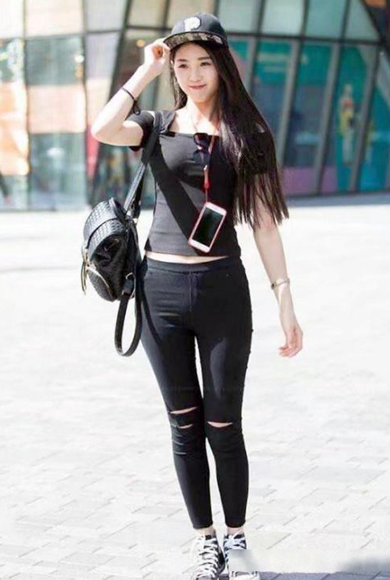 戴着棒球帽的年轻女孩,昂首挺胸地侧身走在大街上