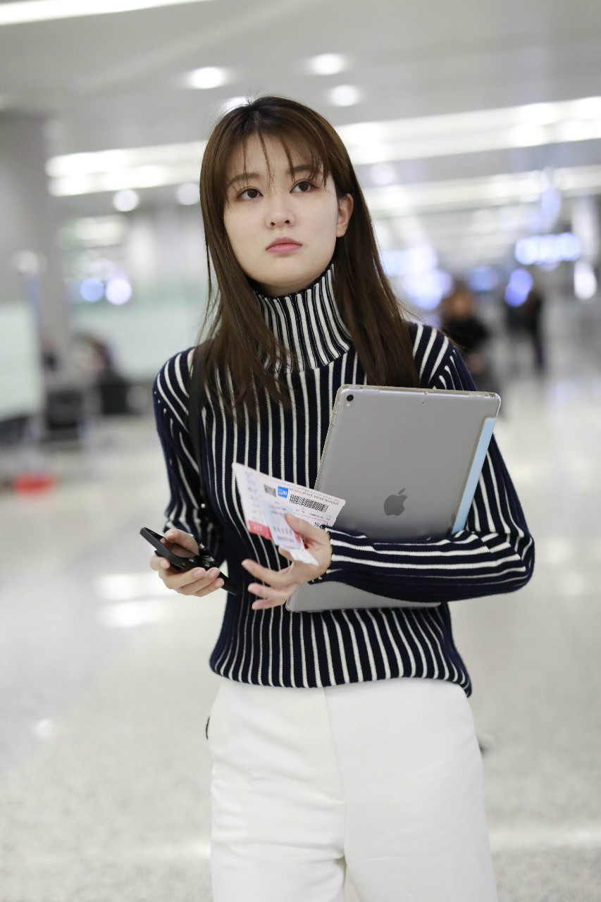 乔欣穿黑白条纹高领毛衣搭配白色裤子现身机场,皮肤白皙面带微笑