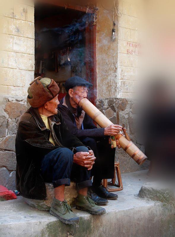 当地农民抽烟大多所用的水烟筒很像内地的吹火筒,只不过吹火筒是往外