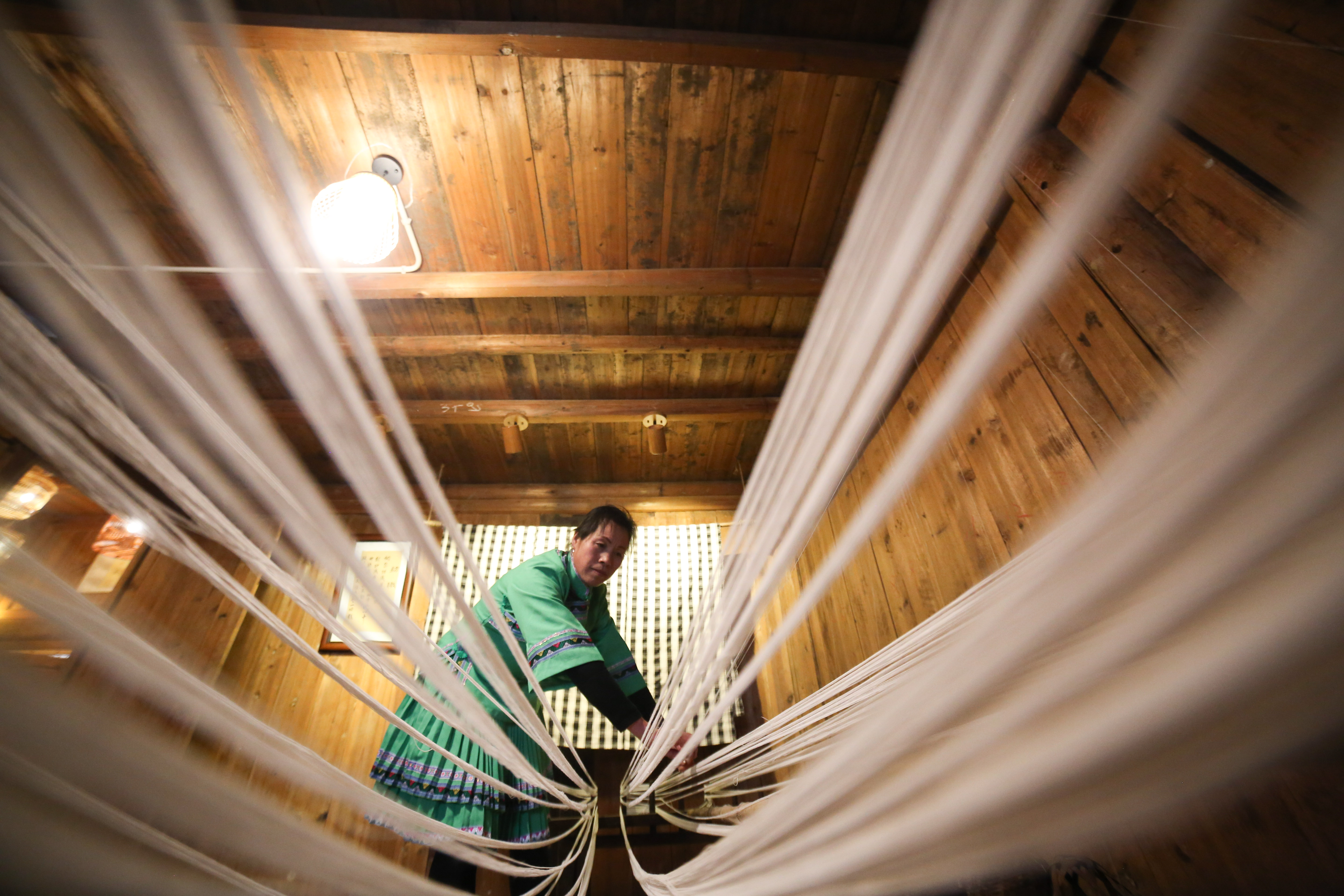 日,在贵州省铜仁市玉屏侗族自治县新店镇老寨村,一名侗族妇女准备织布