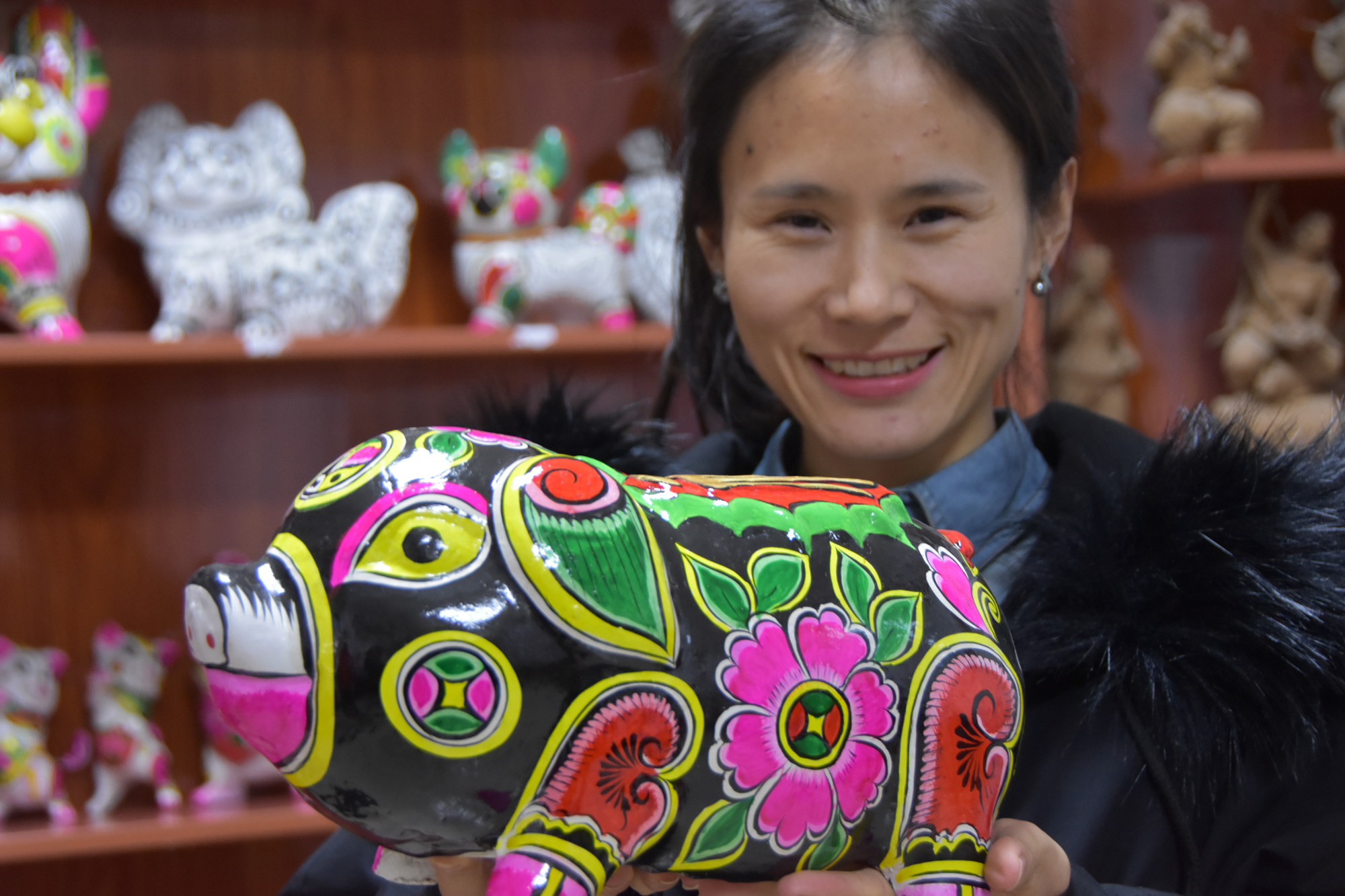 12月20日,一名凤翔县六营村的泥塑艺人在展示一件泥塑猪作品.