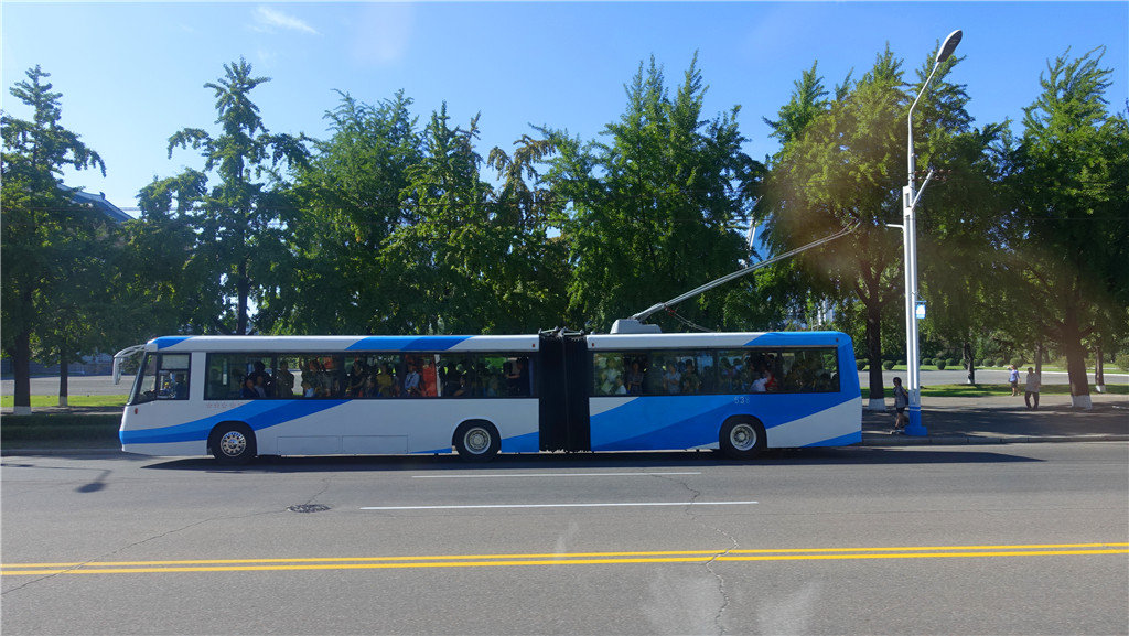 图为朝鲜平壤马路上一辆出租车驶过,马路两旁的绿化很好.