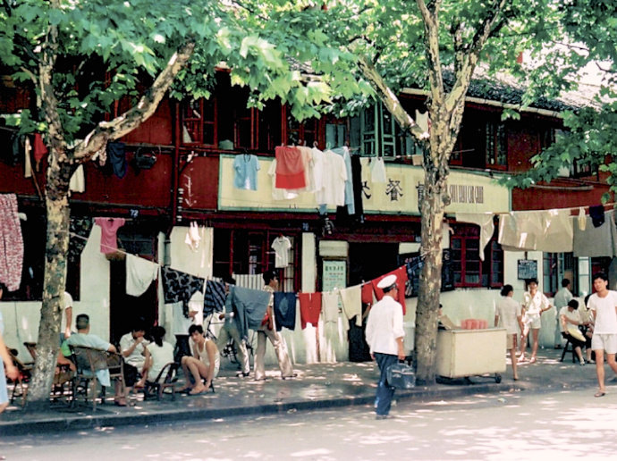 图为在房屋前,道路旁乘凉的人们,每个人都是悠然自得的样子,不像今天