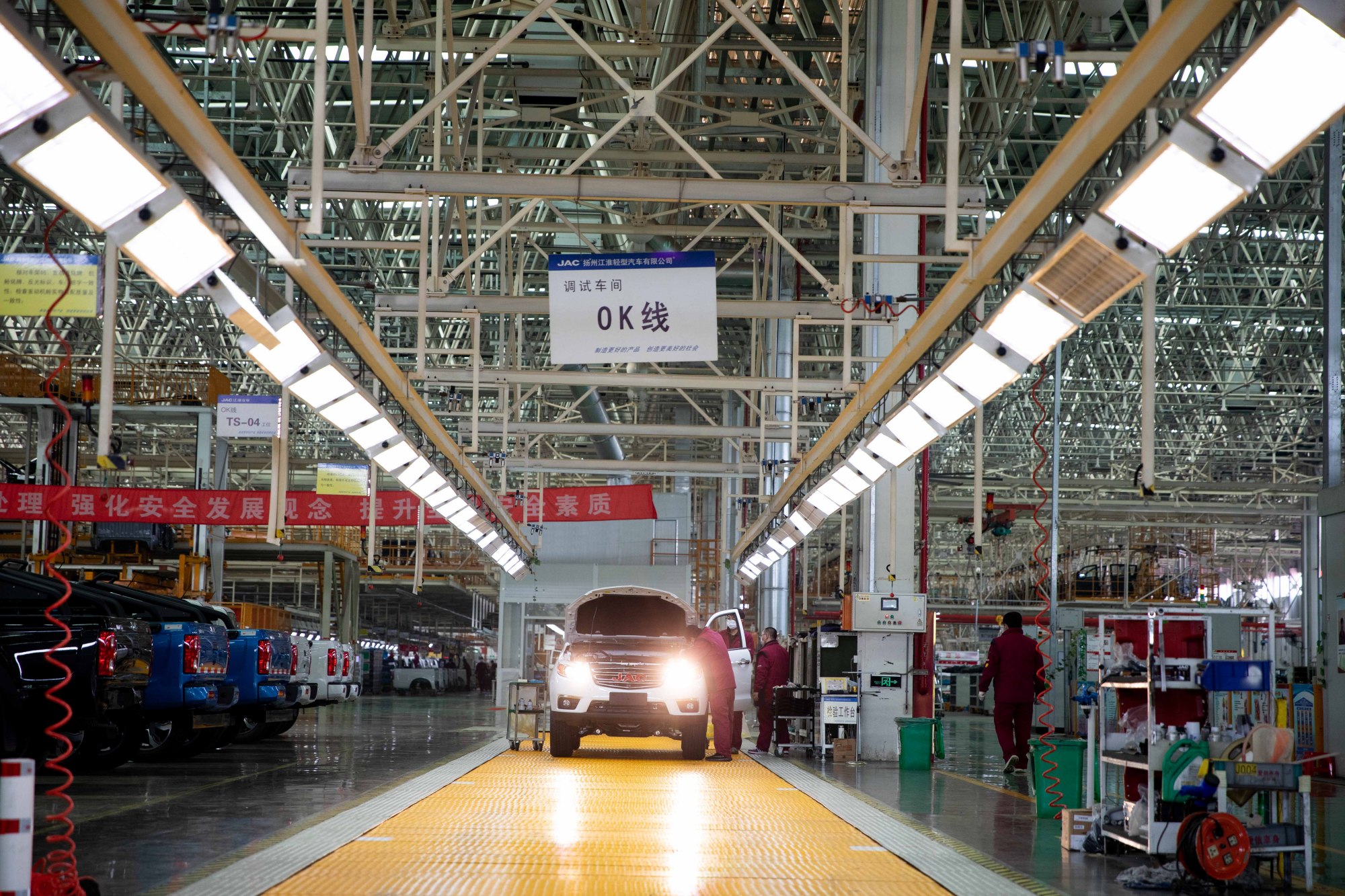 扬州江淮轻型汽车有限公司焊接车间内,焊接机器人灵活地摆动手臂;总装