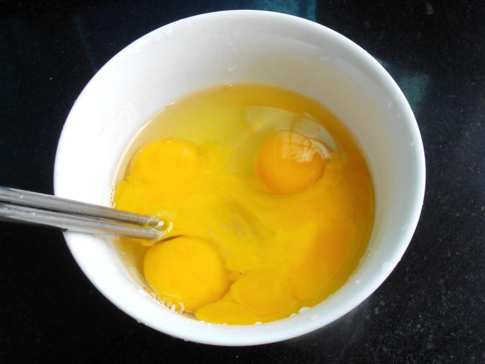 拿出一些鸡蛋,然后如图所示把鸡蛋打入碗里,之后把鸡蛋的蛋黄和蛋清