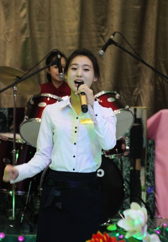 图为一名穿着白色衬衣唱歌的朝鲜女子,颜值非常高,而且多才多艺.