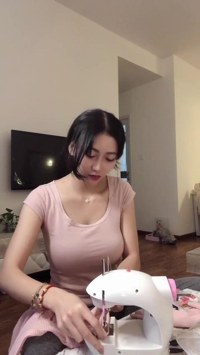 认真缝衣服的时尚美女,穿着紧身t恤,显得韵味十足