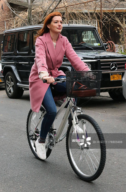 安妮·海瑟薇骑脚踏车漫游纽约街头 粉嫩大衣配红发甜美暴击