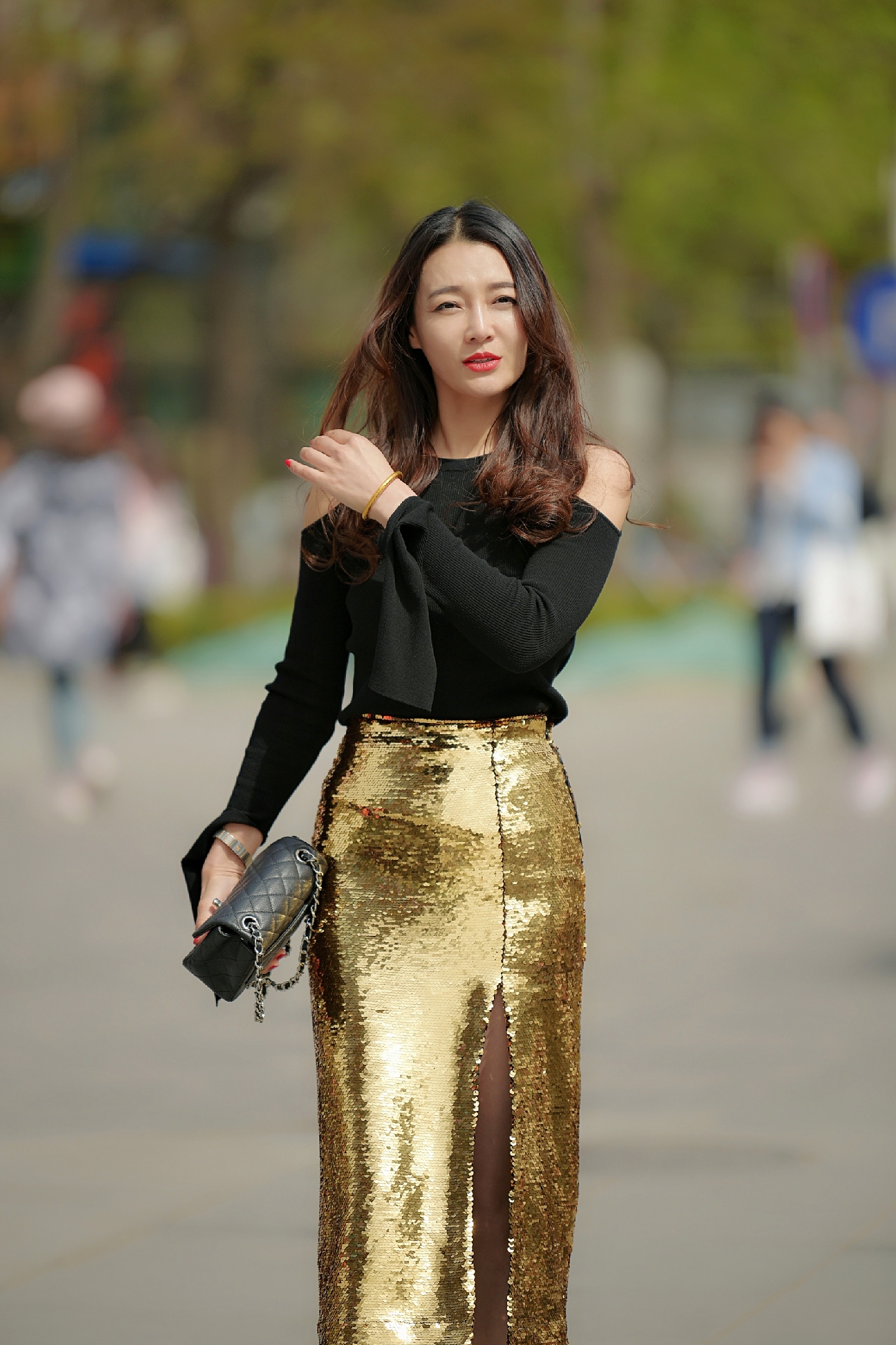 小姐姐穿着一款bling bling的金色长筒裙,裙子侧开衩的设计,美丽时尚