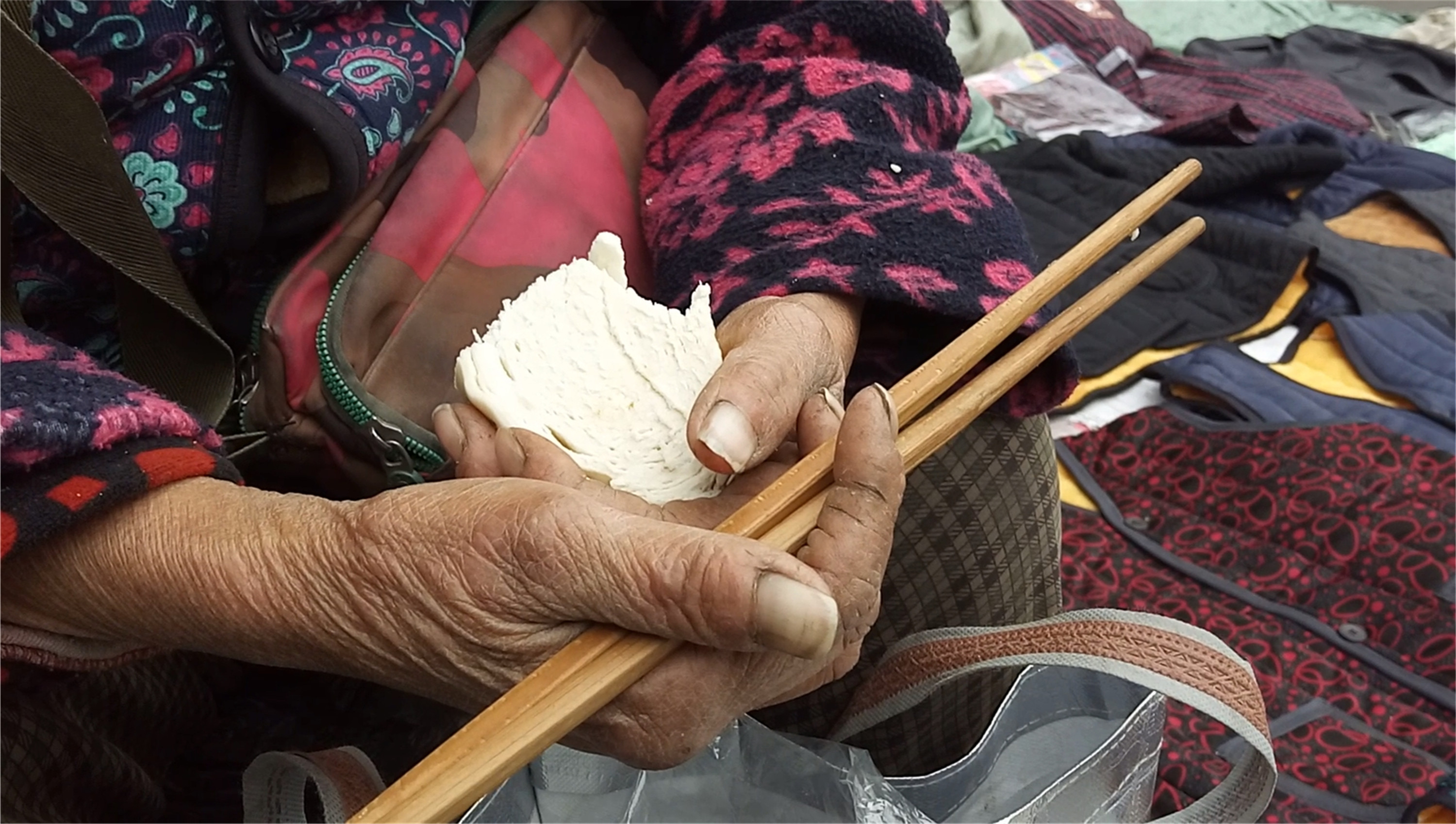 6旬老人摆摊卖衣数年 寒冬街头凉馍当午餐