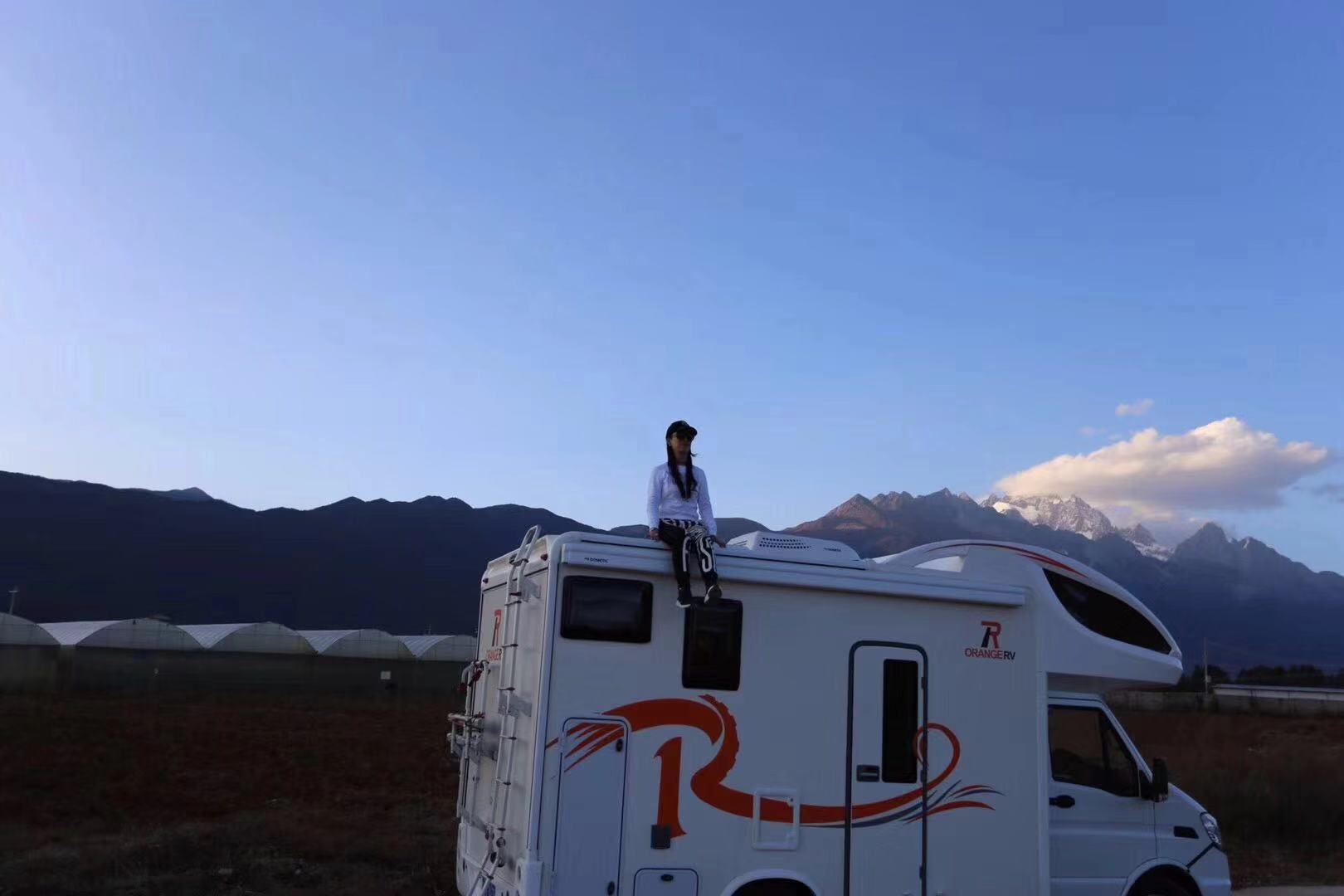 以蓝天雪山为背景,坐在车顶眺望远方.
