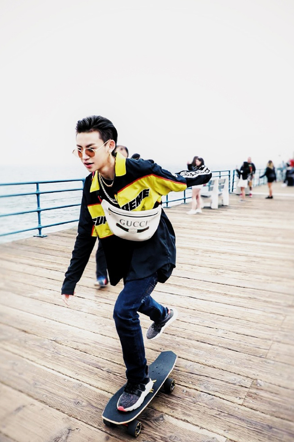 穿着黄黑相间的外套,带着斜跨包的王琳凯非常酷帅,踩着滑板的样子很有