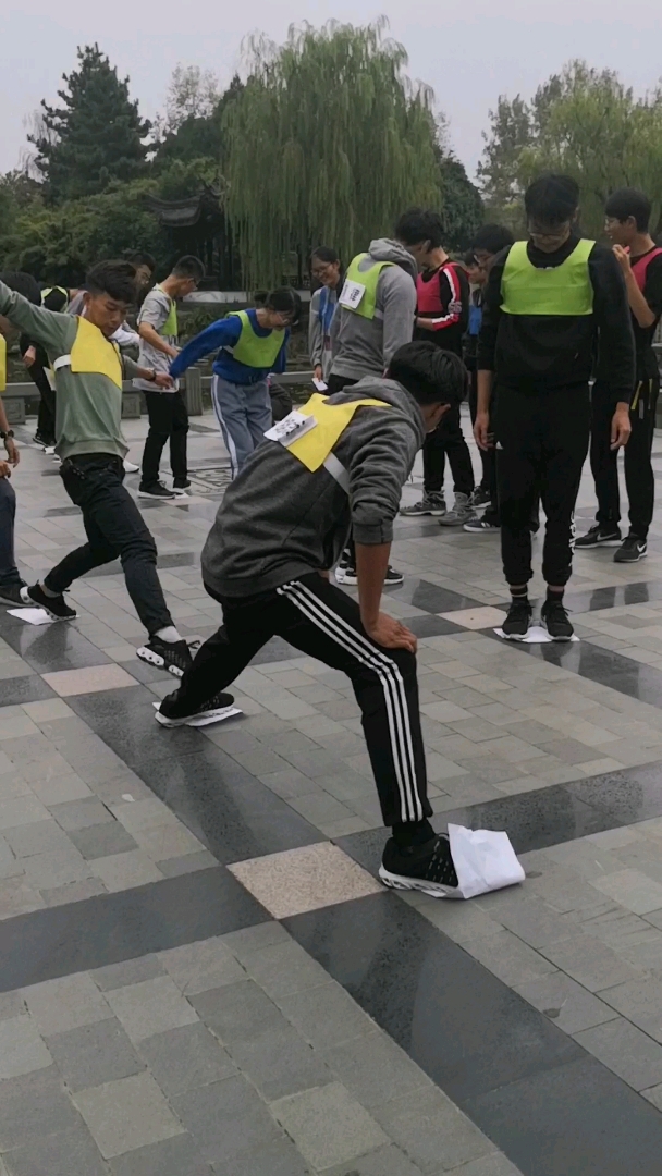 学生们公园在做脚踩纸的游戏