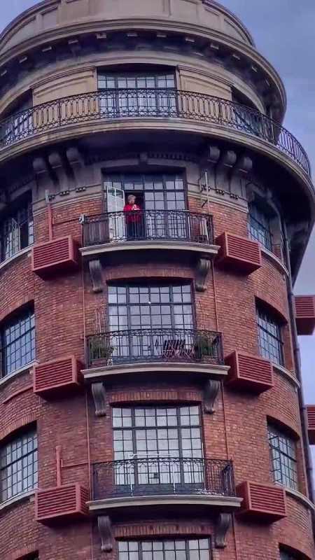 上海交叉路口阳台上的红衣奶奶在认真观察楼下的人来人往