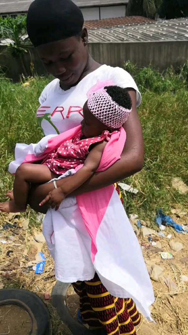 这个小黑婆听说老公要回来了,就抱着孩子站在这里等着