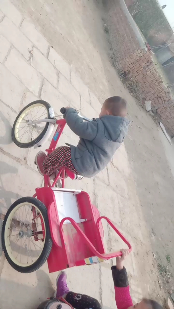 这小孩会骑三轮车了