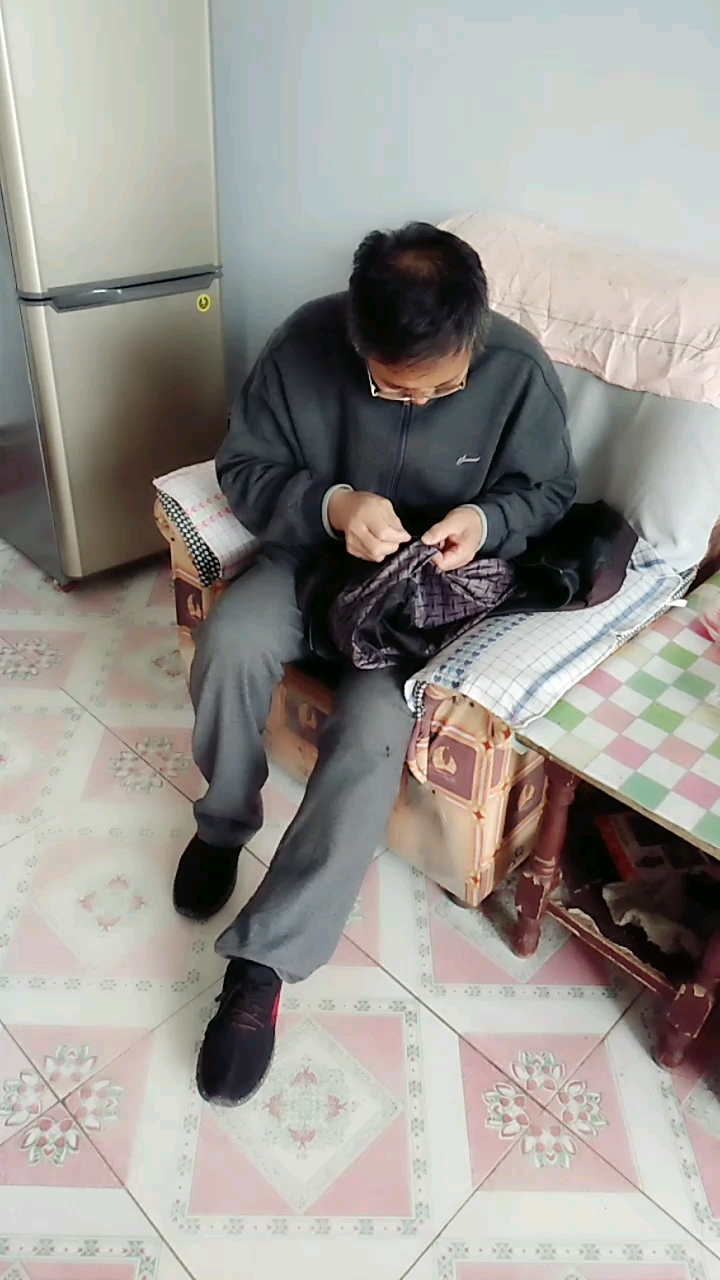 老大爷帮大妈缝衣服动作姿势还挺投入.