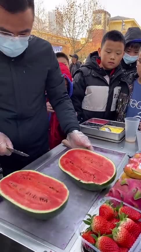 小哥在校门口摆摊卖炒冰,一天要切50个西瓜,每天小学生都是他的老顾客